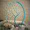 light blue and electric blue wire tree of life created in a metal hoop displayed in bed of river rock